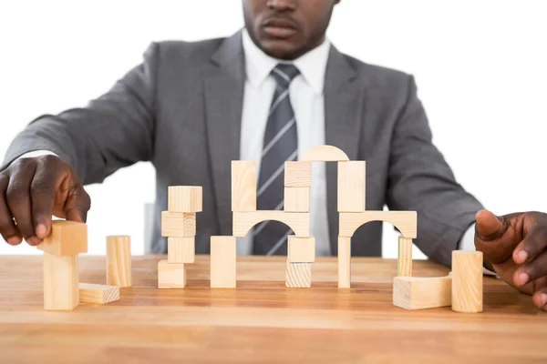 Businessman building tower of wooden blocks — Stock Photo, Image
