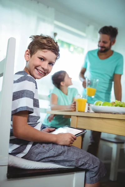 Menino usando tablet digital com café da manhã na mesa — Fotografia de Stock