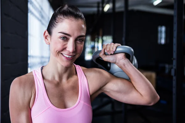 Smiling atleta femminile sollevamento kettlebell — Foto Stock