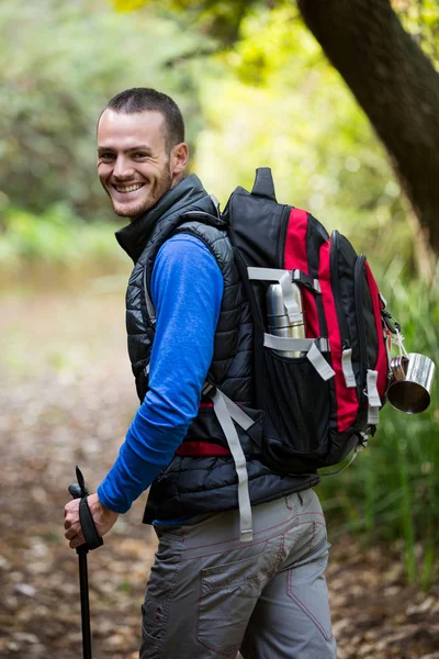 Senderista masculino sonriente caminando con bastón de senderismo —  Fotos de Stock