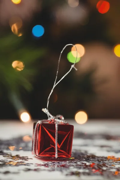 Pequena caixa de presente embrulhada e floco de neve espalhados na mesa — Fotografia de Stock