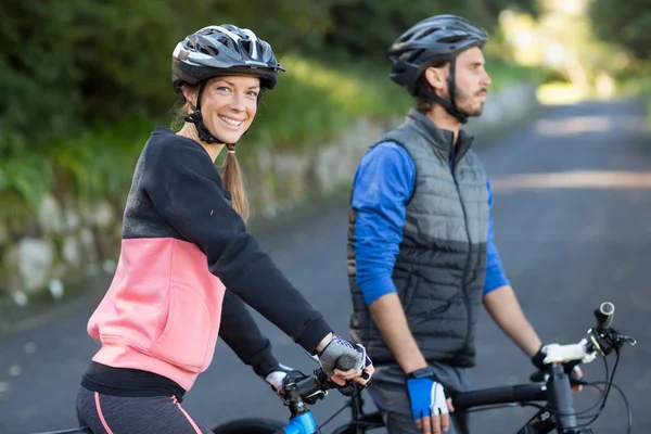 Biker couple with mountain bike on the road — Stock Photo, Image