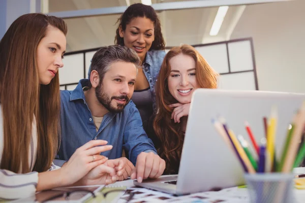 Mulheres de negócios com colegas de trabalho do sexo masculino usando laptop — Fotografia de Stock