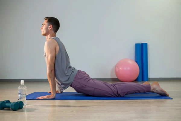 Man doing cobra pose on exercise mat — Stock Photo, Image