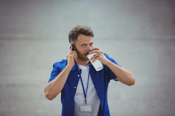 Мужчина пьет кофе, разговаривая по телефону — стоковое фото
