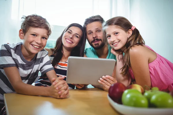 테이블에 앉아있는 동안 디지털 태블릿을 사용 하 여 가족 — 스톡 사진