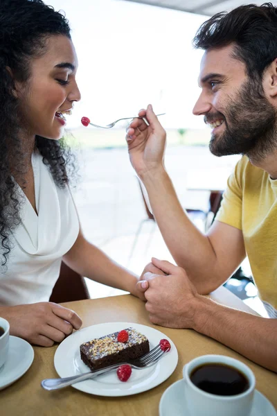 Man feeding pastry cherry to woman — Stock Photo, Image