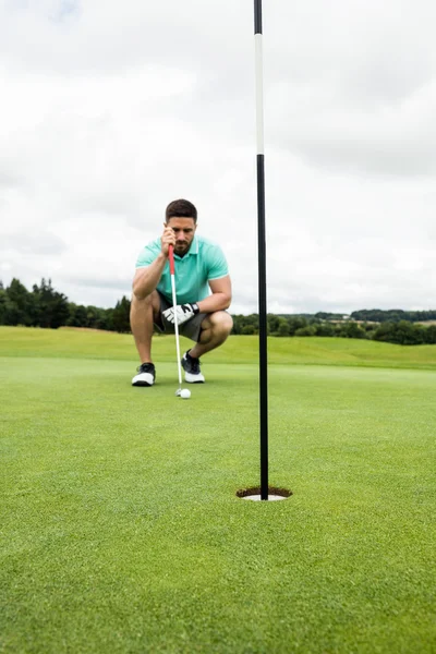 Man squatting to line up his putt — Stock Photo, Image