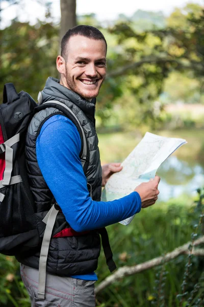 Caminhante masculino segurando um mapa na floresta — Fotografia de Stock