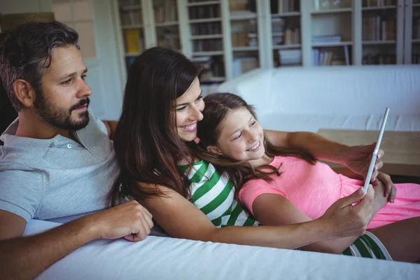 Батьки на дивані з дочкою використовують планшет — стокове фото