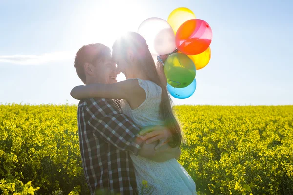 Pareja sosteniendo globos de colores y abrazando —  Fotos de Stock