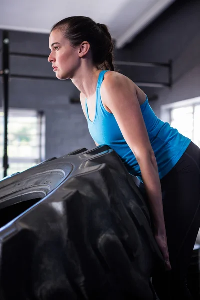 Lekkoatletka pchanie opon w siłowni — Zdjęcie stockowe