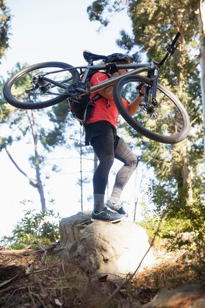 Mężczyzna mountain biker przewozu rowerów w lesie — Zdjęcie stockowe