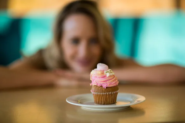 Mulher olhando para cupcake no prato — Fotografia de Stock