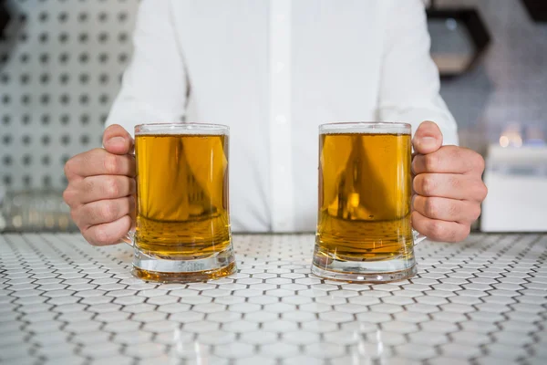 Cantinero sosteniendo dos vasos de cerveza — Foto de Stock