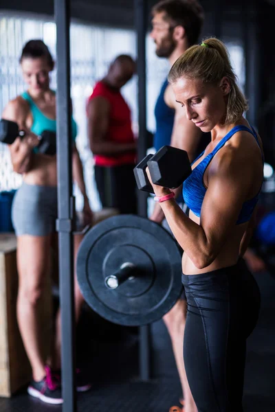 Jeune femme tenant haltères dans la salle de gym — Photo