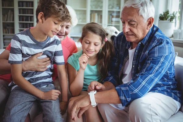 Prarodiče a vnuci, při pohledu na hodinky smartwatch — Stock fotografie