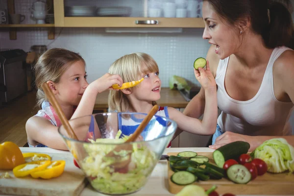 Kinderen voeden een schijfje courgette aan moeder — Stockfoto