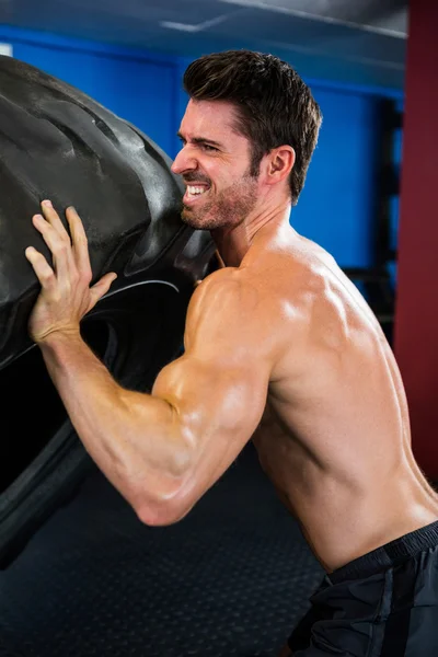 Shirtless male athlete lifting tire — Stock Photo, Image