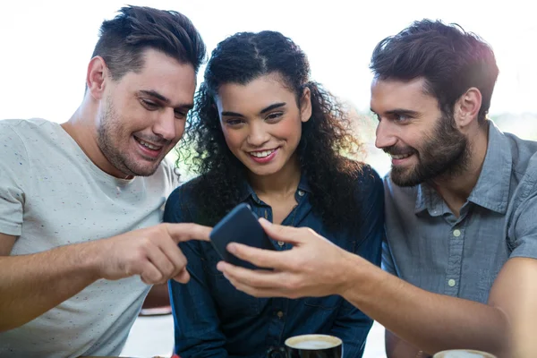Three friends using phone in coffee shop — Stock Photo, Image