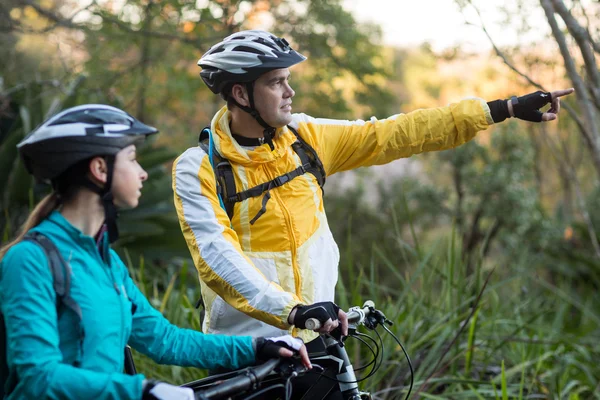 Biker casal com bicicleta de montanha apontando na distância — Fotografia de Stock