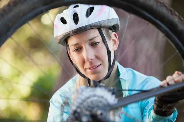 Feminino mountain biker examinando roda — Fotografia de Stock