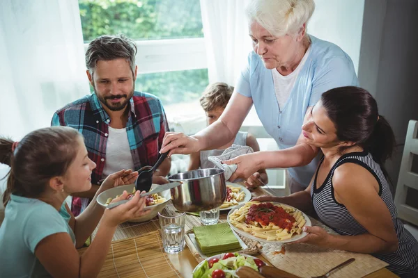 Elderly woman  serving meal to her family — Stock Photo, Image