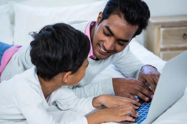 Far och son med laptop på sängen — Stockfoto