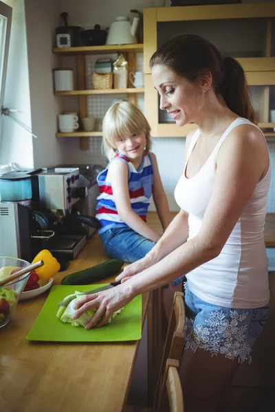 Mother chopping vegetables and daughter watching her — Stock Photo, Image