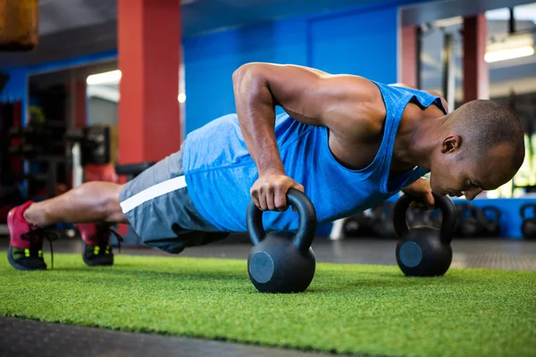 Doen push-ups met kettlebells atleet — Stockfoto