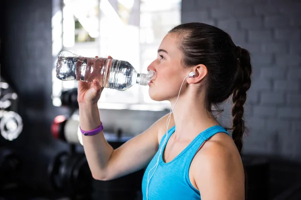 Vrouwelijke atleet drinkwater in sportschool — Stockfoto