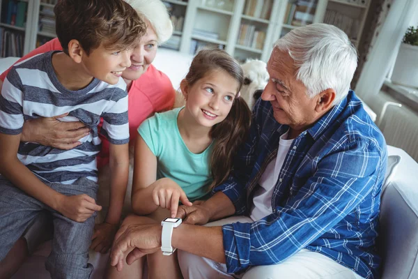 Far-och morföräldrar och barnbarn tittar på smartwatch — Stockfoto