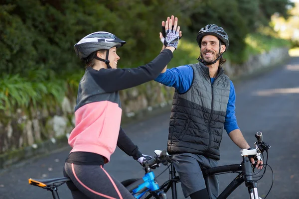 Pareja motociclista dando cinco altos mientras monta bicicleta —  Fotos de Stock