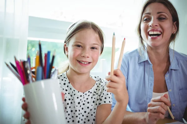 Daughter next to mother and showing color pens — Stockfoto