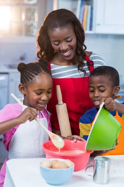 Crianças preparando bolo com sua mãe — Fotografia de Stock