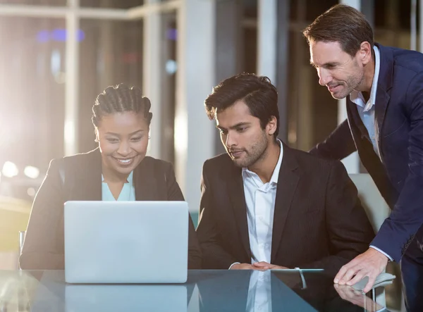 Empresária discutindo com colegas sobre laptop — Fotografia de Stock