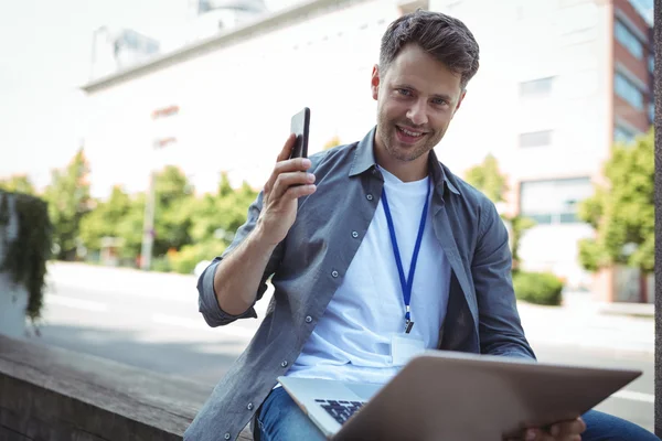 Business executive holding phone and laptop — Stock Photo, Image