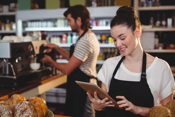 Waitress standing at counter using tablet — Stock Photo, Image