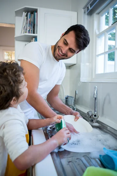 Син допомагає батькові у митті посуду — стокове фото
