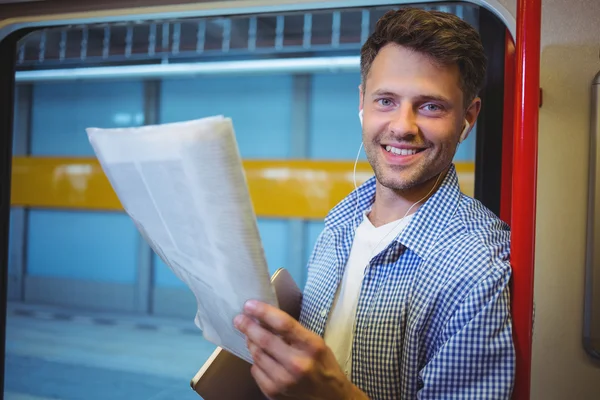 Homem segurando jornal enquanto ouve música — Fotografia de Stock