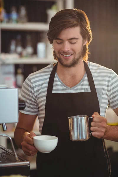 Улыбающийся официант делает чашку кофе — стоковое фото