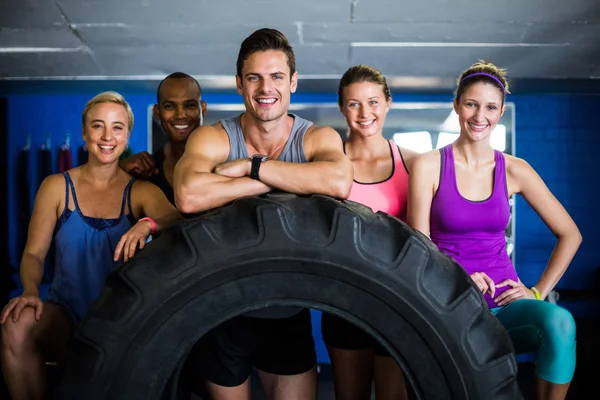 Amis souriants avec pneu dans la salle de gym — Photo