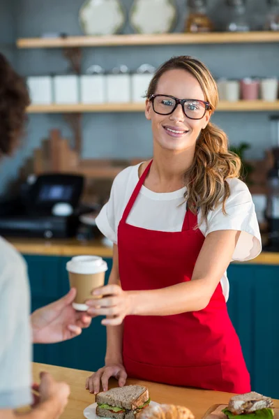 Waitress serving a coffee to customer at counter — Stock Photo, Image