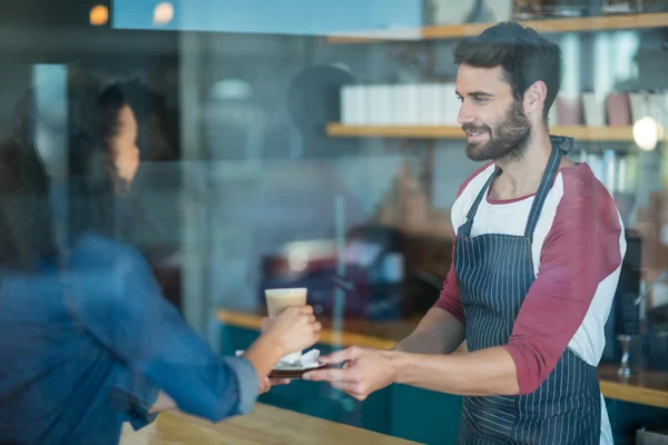 Waiter serving coffee to customer at counter — Stock Photo, Image