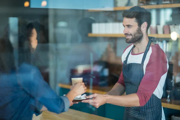 Servitör serverar kaffe till kund på counter — Stockfoto