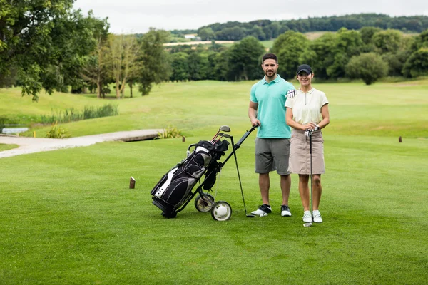 Pár stojící s golfovou hůl a pytel — Stock fotografie