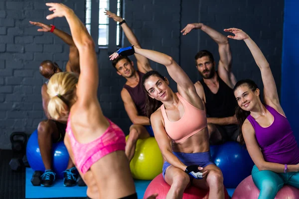 Athletes exercising with instructor in gym — Stock Photo, Image