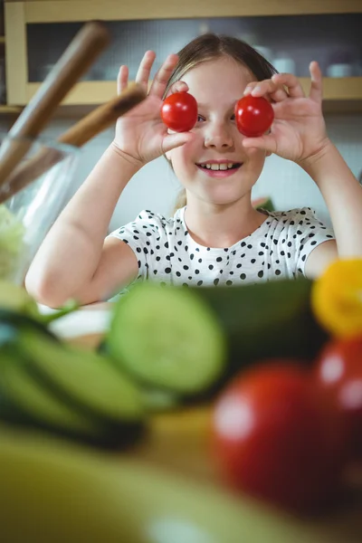 Chica juguetona sosteniendo tomate cherry en su ojo — Foto de Stock