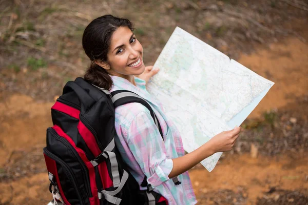 Senderista femenina sosteniendo mapa en el bosque — Foto de Stock