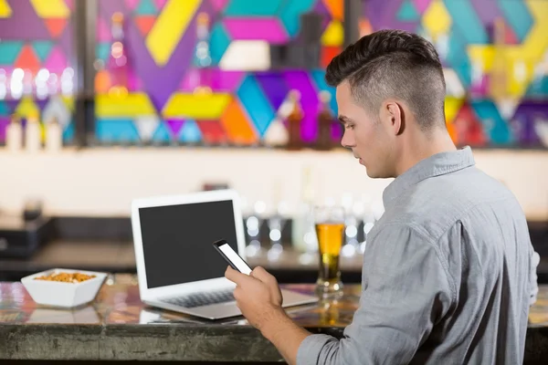 Homme utilisant téléphone avec ordinateur portable sur la table — Photo